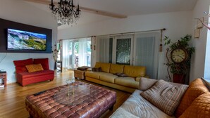 A living room with a red sofa, a yellow sofa, a brown ottoman, and a large flat-screen TV mounted on the wall. - Deluxe loft 150 sqm with 2 bedrooms for 1-6 persons and balcony (Bad Reichenhall)