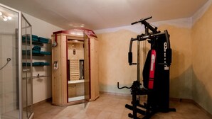 Ein kleines Zimmer mit Sauna, Dusche und Fitnessgerät.