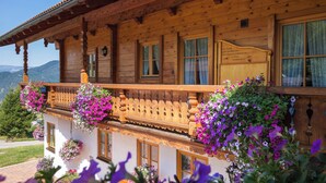 Un chalet en bois doté de balcons, de rampes en bois et de jardinières suspendues.