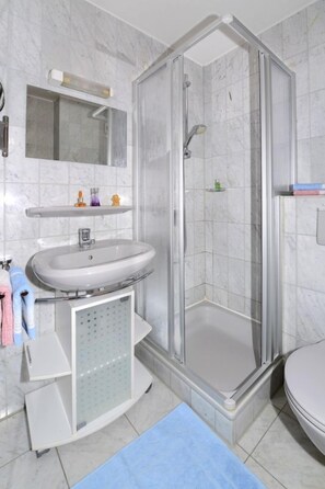 A bathroom with a glass-enclosed shower, a sink, and a mirror. - Ferienwohnung am Hauchen (Reit im Winkl)