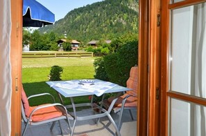 Relax on the patio with a table and two chairs, overlooking a beautifully manicured lawn and the surrounding mountains.