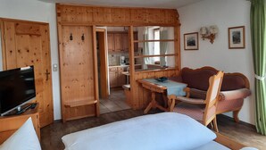 Una camera accogliente con un letto, una TV, un tavolo da pranzo in legno e un divano.