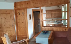Un intérieur en bois comprenant un coin repas, une cuisine avec des meubles en bois et une salle de bain visible à travers une porte ouverte.