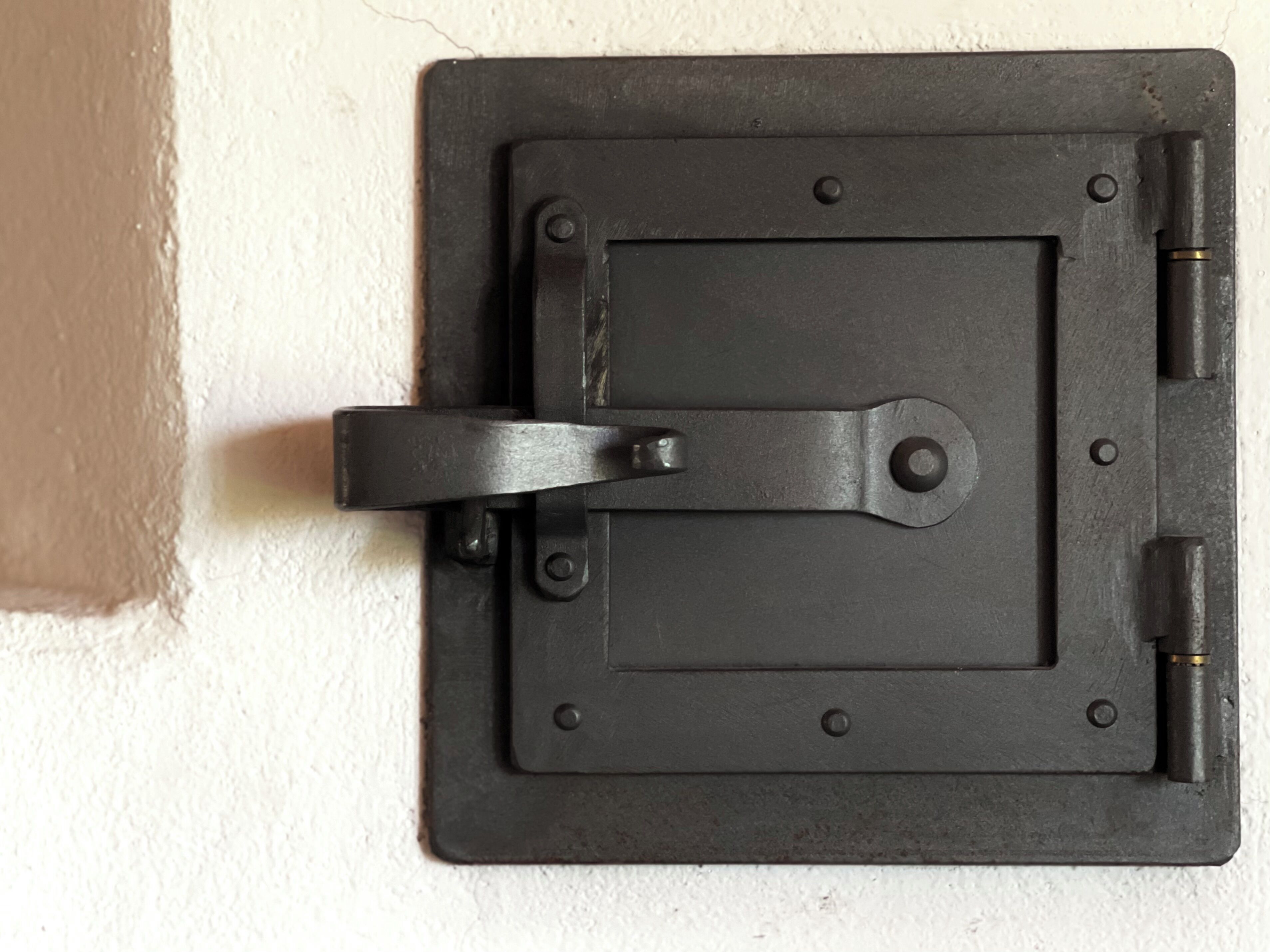 A black metal latch on a white wall.