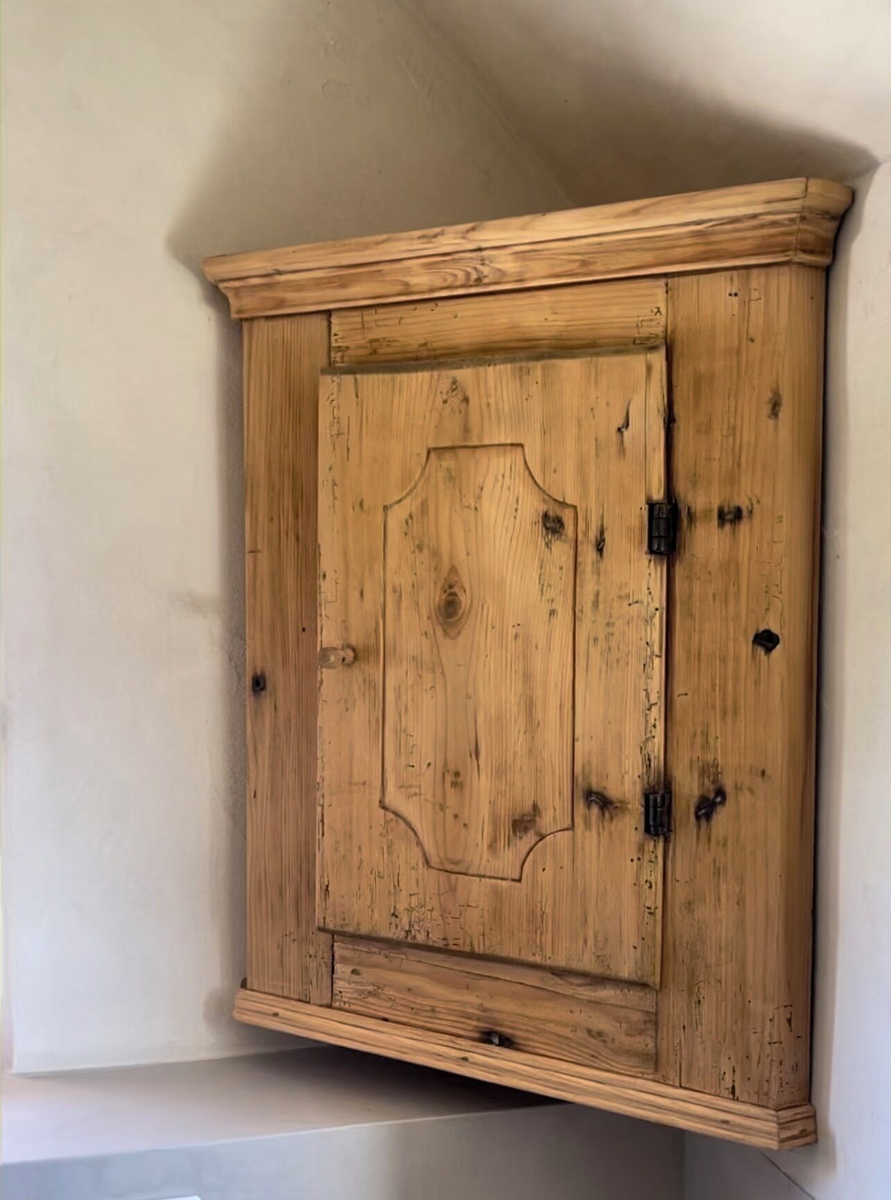 A wooden cabinet with a simple design, located in a corner of a room.