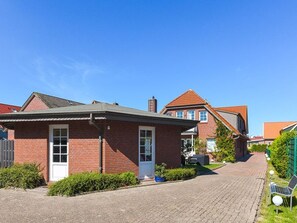 Une rue résidentielle bordée de maisons en briques, avec une allée pavée et un banc.