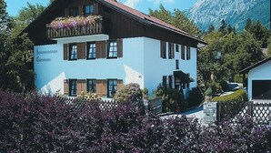 A two-story building with a blue facade and a wooden upper floor. - Stylish apartment with mountain view (St2)/Steilhofweg. 50 sqm, 1 bedroom (Bayerisch Gmain)