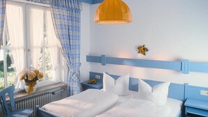A bedroom with a bed, a chair, a nightstand, a window with curtains, and a hanging light fixture. - Stylish apartment with mountain view (St2)/Steilhofweg. 50 sqm, 1 bedroom (Bayerisch Gmain)