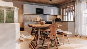 A kitchen with wooden cabinets, a microwave, and a dining table with chairs. - (8) Vier-Raum-Ferienwohnung 85qm, 2 Bäder, 3 Schlafzimmer, Küche und Balkon (Reit im Winkl)