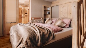 A bedroom with a bed, a wooden wardrobe, a bookshelf, and a shower area. - (8) Vier-Raum-Ferienwohnung 85qm, 2 Bäder, 3 Schlafzimmer, Küche und Balkon (Reit im Winkl)