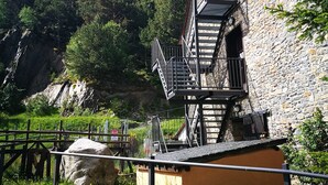 A stone building with a sign reading "ALBERGO LES DAINS." It features a staircase leading to an upper level with a balcony. - Alberg Les Daines (Espot)