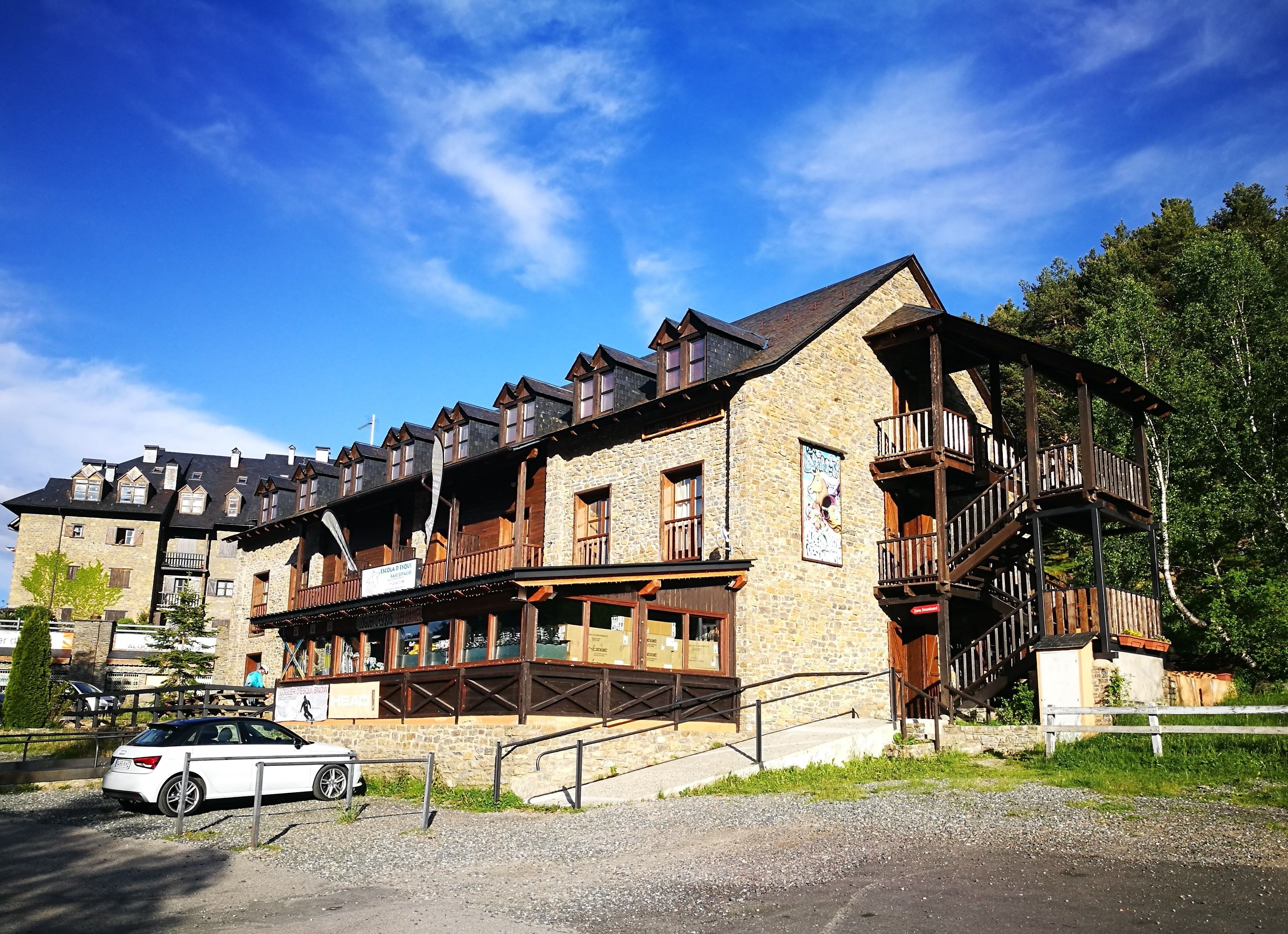 A traditional stone building with wooden balconies and a staircase leading to an upper level.