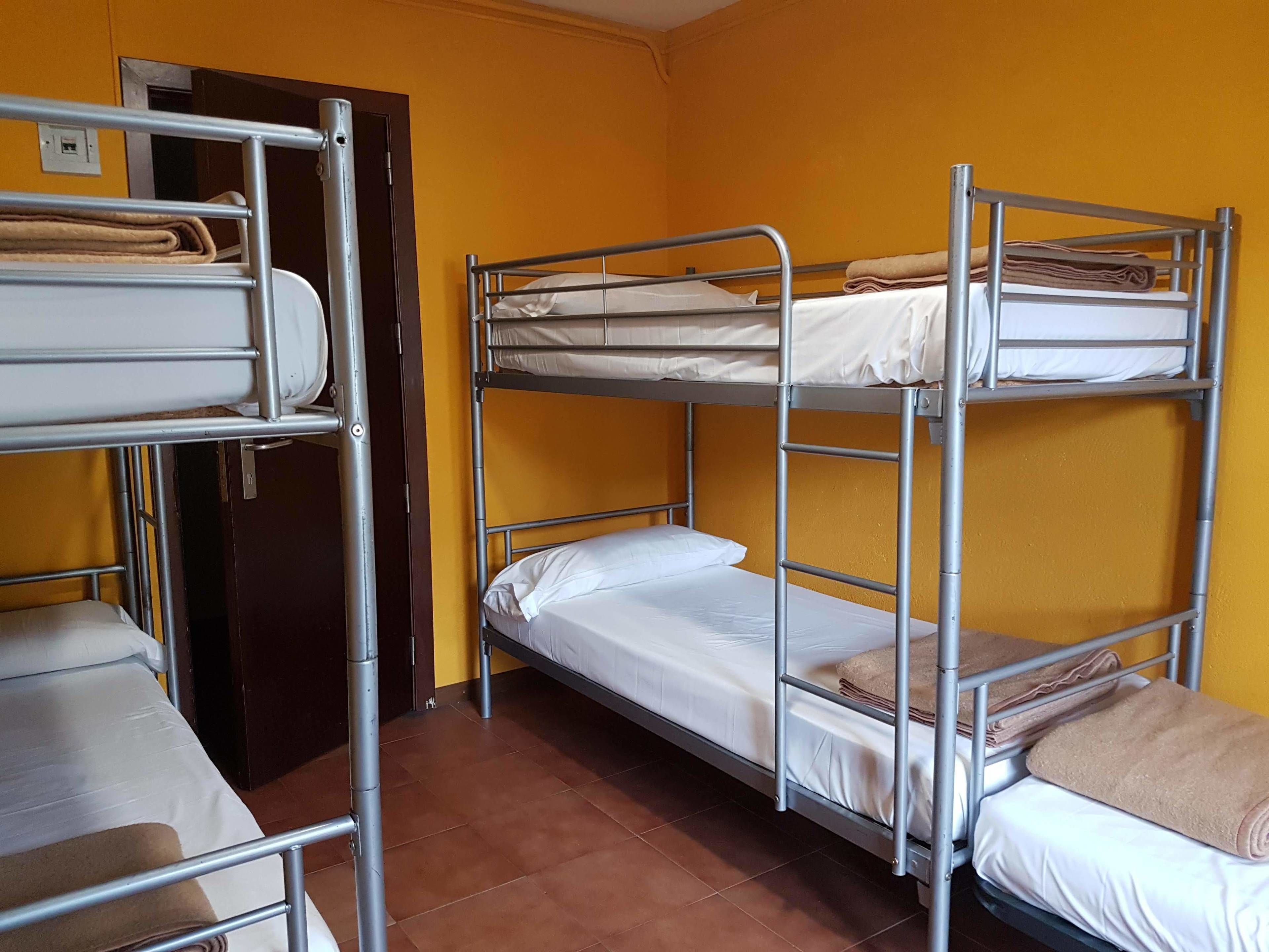A dormitory room with bunk beds, a door, and a tiled floor.