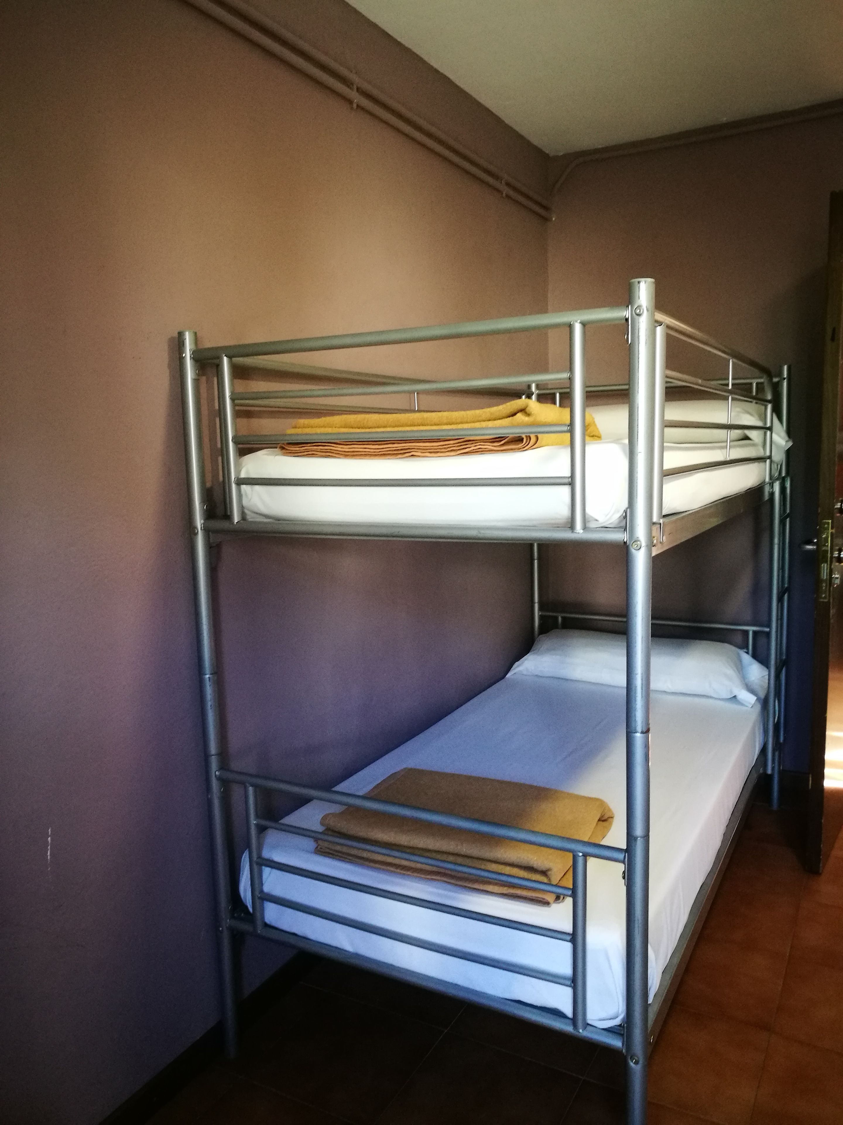 A bunk bed with metal railings and a mattress on the top bunk.