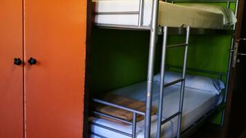 A bunk bed with metal railings and a wooden headboard, set against a green wall.
