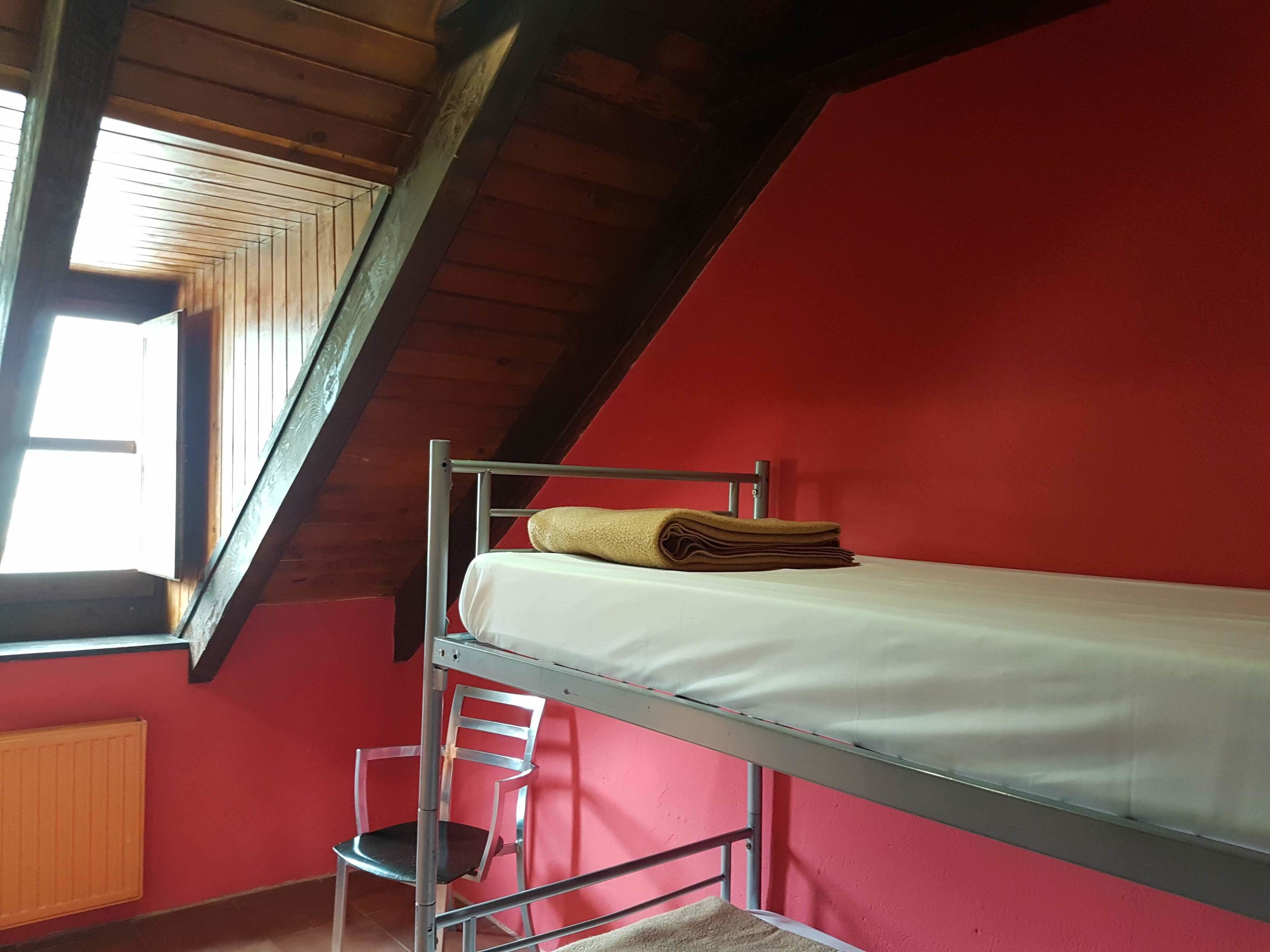 Quarto de dormitório com beliche, cadeira e janela.