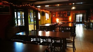 A restaurant with wooden tables and chairs, a bar area, and a view of the street outside. - Alberg Les Daines (Espot)