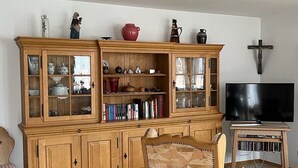 A living room with a wooden cabinet, a television, and a patterned chair. - Ferienwohnung 60 m², 1-2 Personen, Schlafzimmer, Kabel-TV, Balkon, Nichtraucher (Unterwössen)