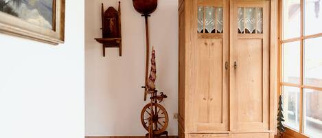 A wooden cabinet with glass doors, a spinning wheel, and a small wooden shelf with decorative items.