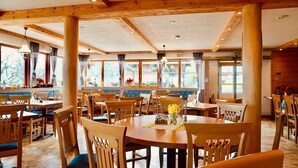 A restaurant with wooden furniture, large windows, and a view of the outdoors. - Vacation apartment 60sqm (Brannenburg)