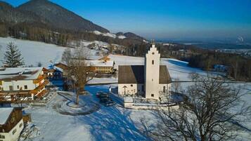 Eine Kirche mit einem Glockenturm, umgeben von schneebedeckten Feldern und Bergen.