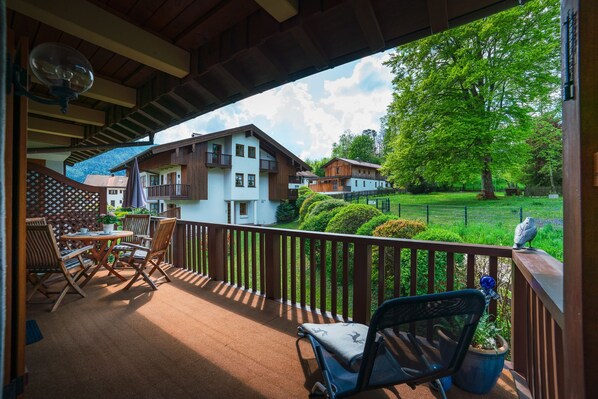 A covered outdoor area with a table and chairs, a view of houses and greenery.