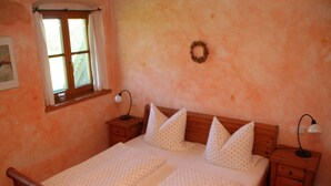 Un letto matrimoniale con struttura in legno, due comodini con lampade, una finestra con tende e una ghirlanda appesa al muro.