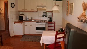 Una cucina compatta con mobili bianchi, un forno a microonde, fornelli e un'area pranzo con tavolo e sedie.