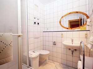 Un baño pequeño con inodoro, lavabo y zona de ducha.