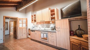 Una cocina moderna con armarios de madera, horno empotrado, televisor de pantalla plana grande y salpicadero de azulejos.