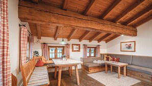 Una habitación acogedora con vigas de madera, una mesa de comedor, un sofá y un banco.