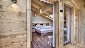 Un interior de madera con cama, mesitas de noche y un taburete.