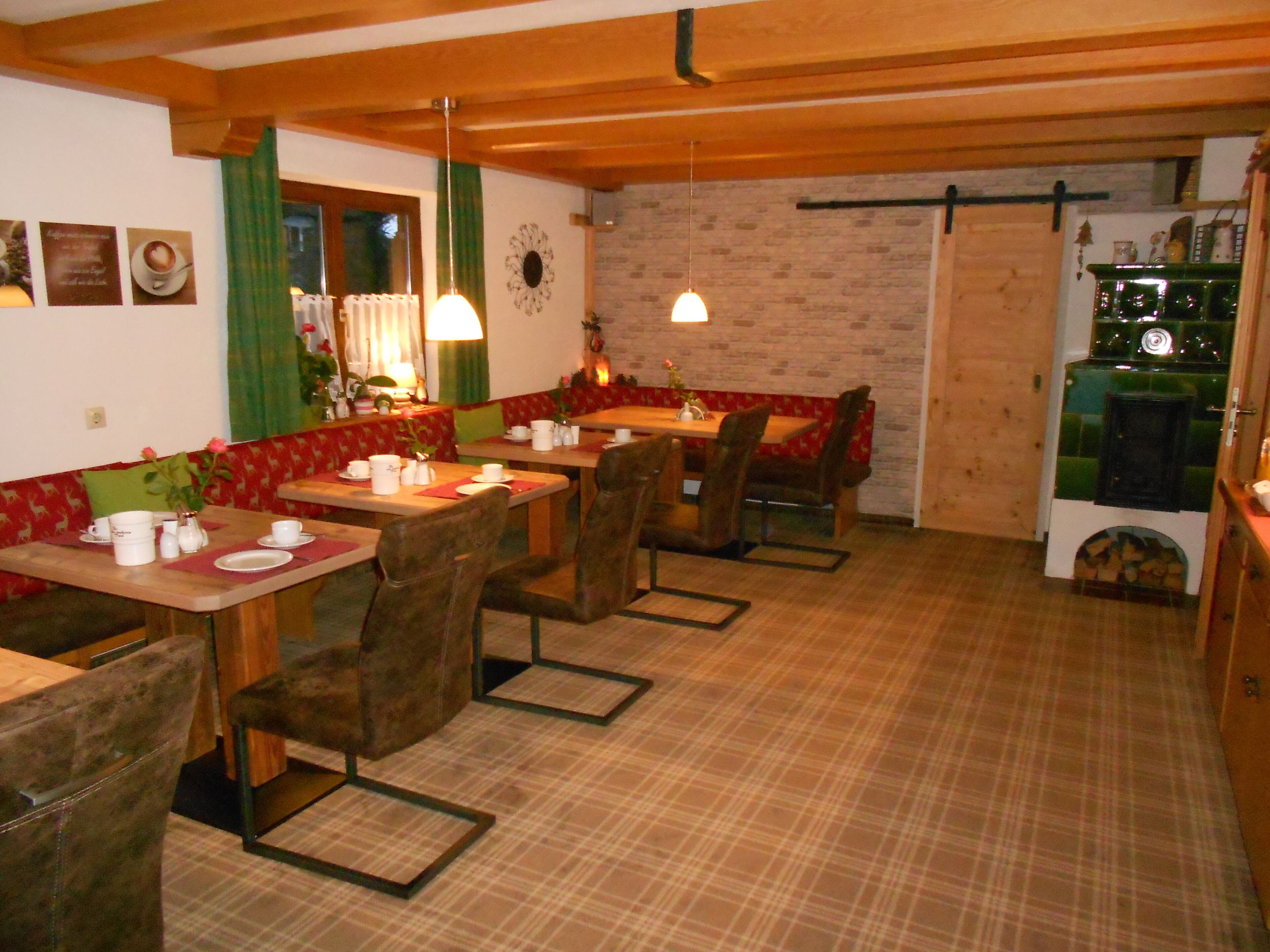 A cozy dining area with wooden tables and benches, a brick wall, and a fireplace.