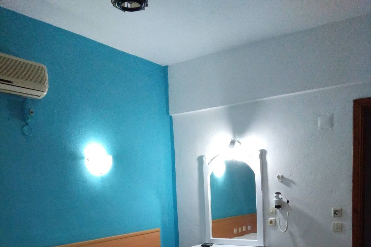 Une chambre d’hôtel équipée d’un lit, d’une table de chevet, d’un miroir et d’un climatiseur fixé au mur.
