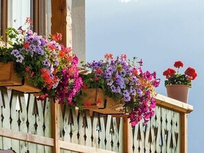A balcony with wooden railings and flower boxes containing a variety of colorful flowers.