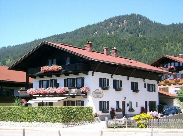 A traditional Alpine-style building with a sloped roof, multiple windows, and flower boxes.