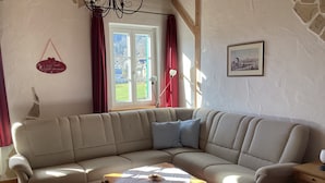 Een gezellige woonkamer met een beige hoekbank, een klein houten salontafel en een vloerkleed met een patroon.