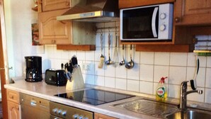 Een keuken met houten kastjes, een roestvrijstalen oven, een magnetron en een spoelbak.