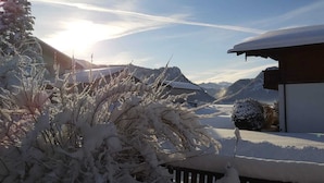 Un paysage enneigé avec une maison et des montagnes en arrière-plan.