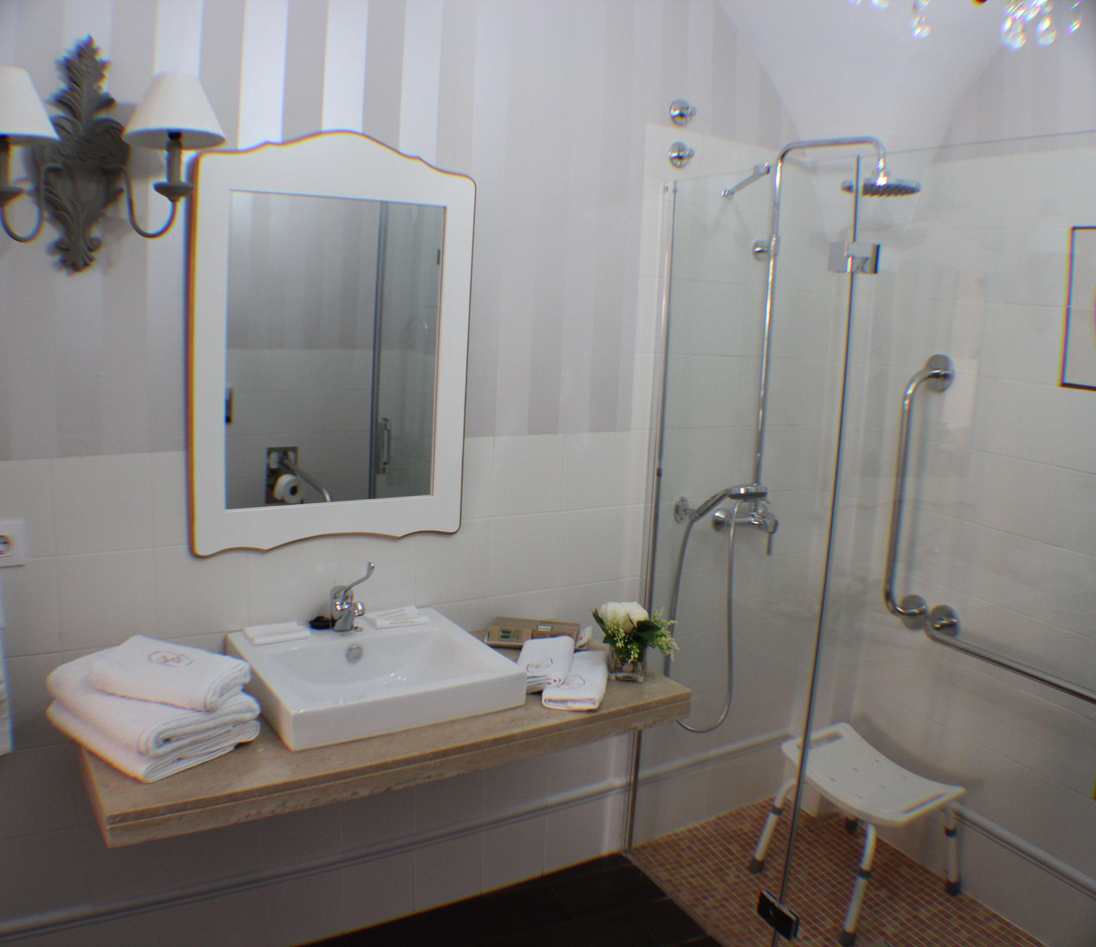 A bathroom with a sink, mirror, and shower.