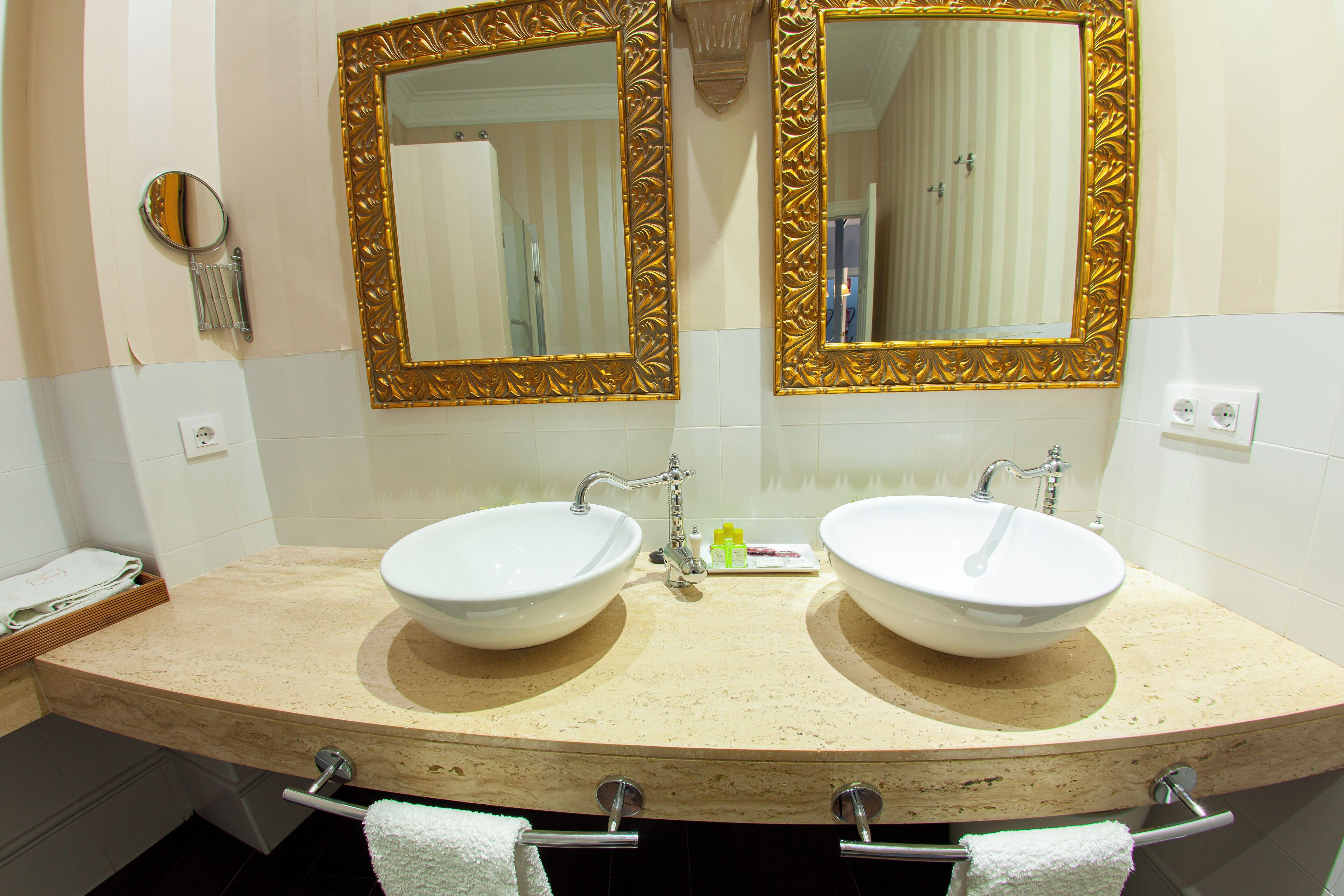 A bathroom with two sinks, two mirrors with ornate frames, and a towel rack with towels.