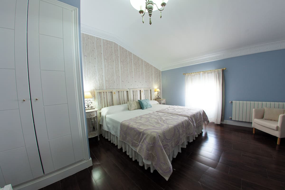 Quarto com cama grande, guarda-roupa, mesa de cabeceira, cadeira e radiador.