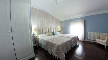 Un dormitorio con una cama grande, un armario, una mesita de noche, una silla y un radiador.