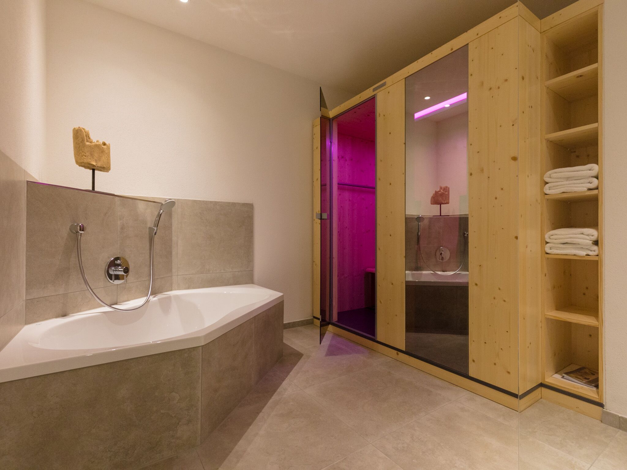 Ein modernes Badezimmer mit freistehender Badewanne, einer Holzeinrichtung für Handtücher und einer Glasdusche.