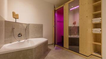Ein modernes Badezimmer mit freistehender Badewanne, einer Holzeinrichtung für Handtücher und einer Glasdusche.