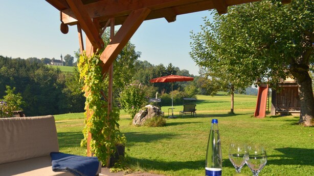 Eine Terrasse mit einem Steintisch, einer Zeitschrift, einer Flasche und Gläsern.
