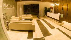 A modern hotel lobby with a reception desk, leather sofas, and a checkered floor. - Native By Chancery Hotels (Belagavi)