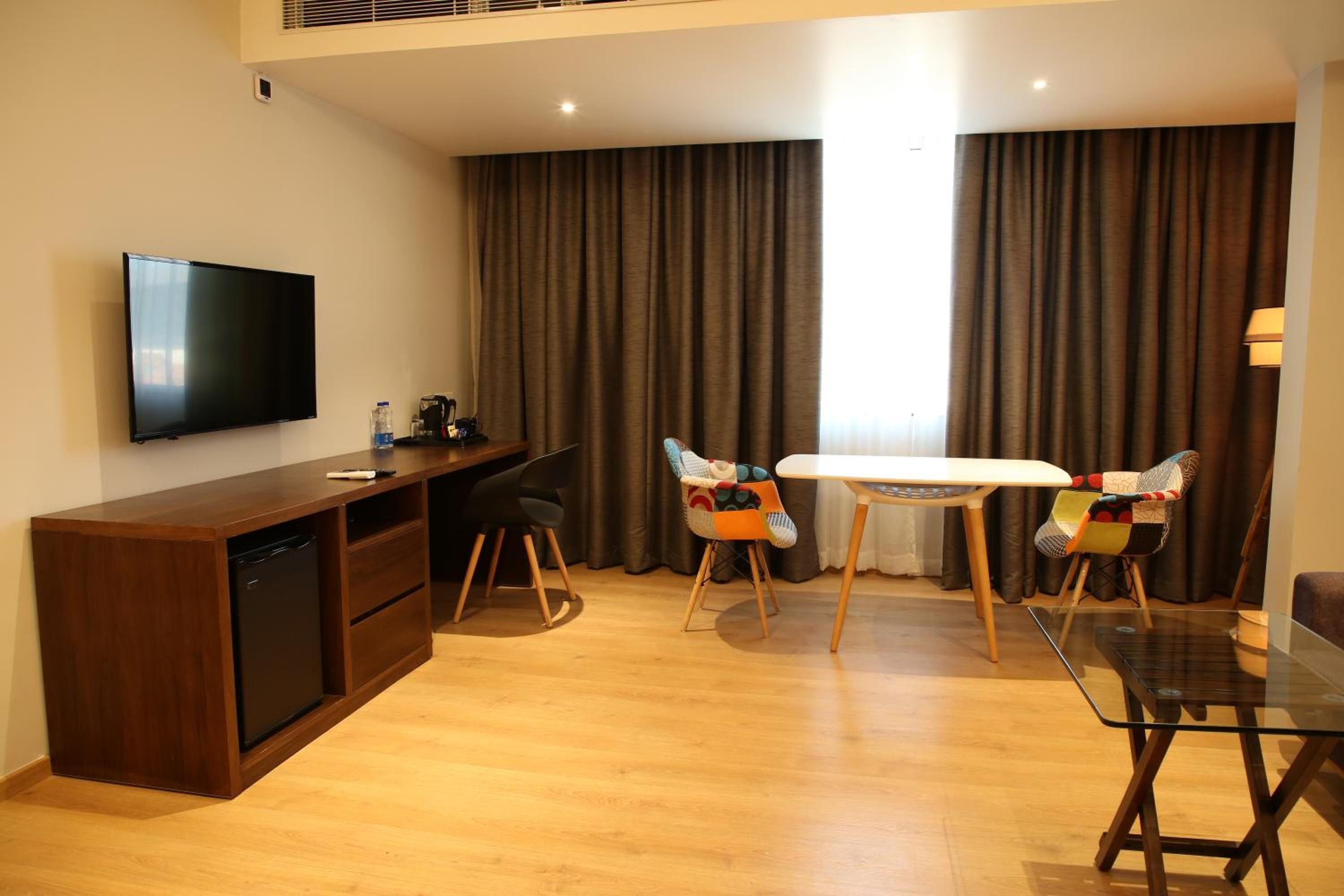 Un salón moderno con un televisor de pantalla plana, muebles de madera, una mesa de comedor y un sofá.