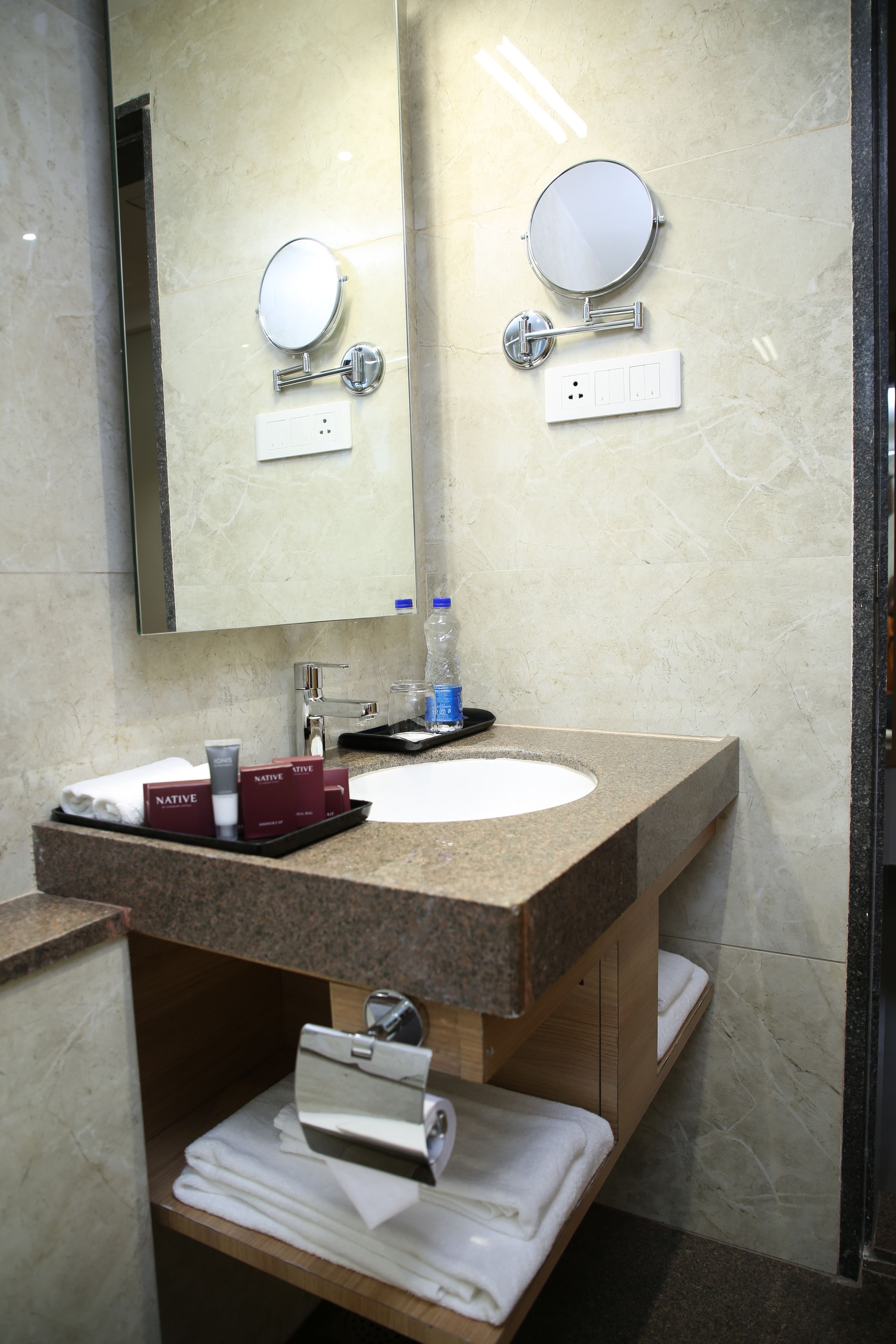 Un baño moderno con un lavabo de mármol, un espejo grande y un perchero para toallas.