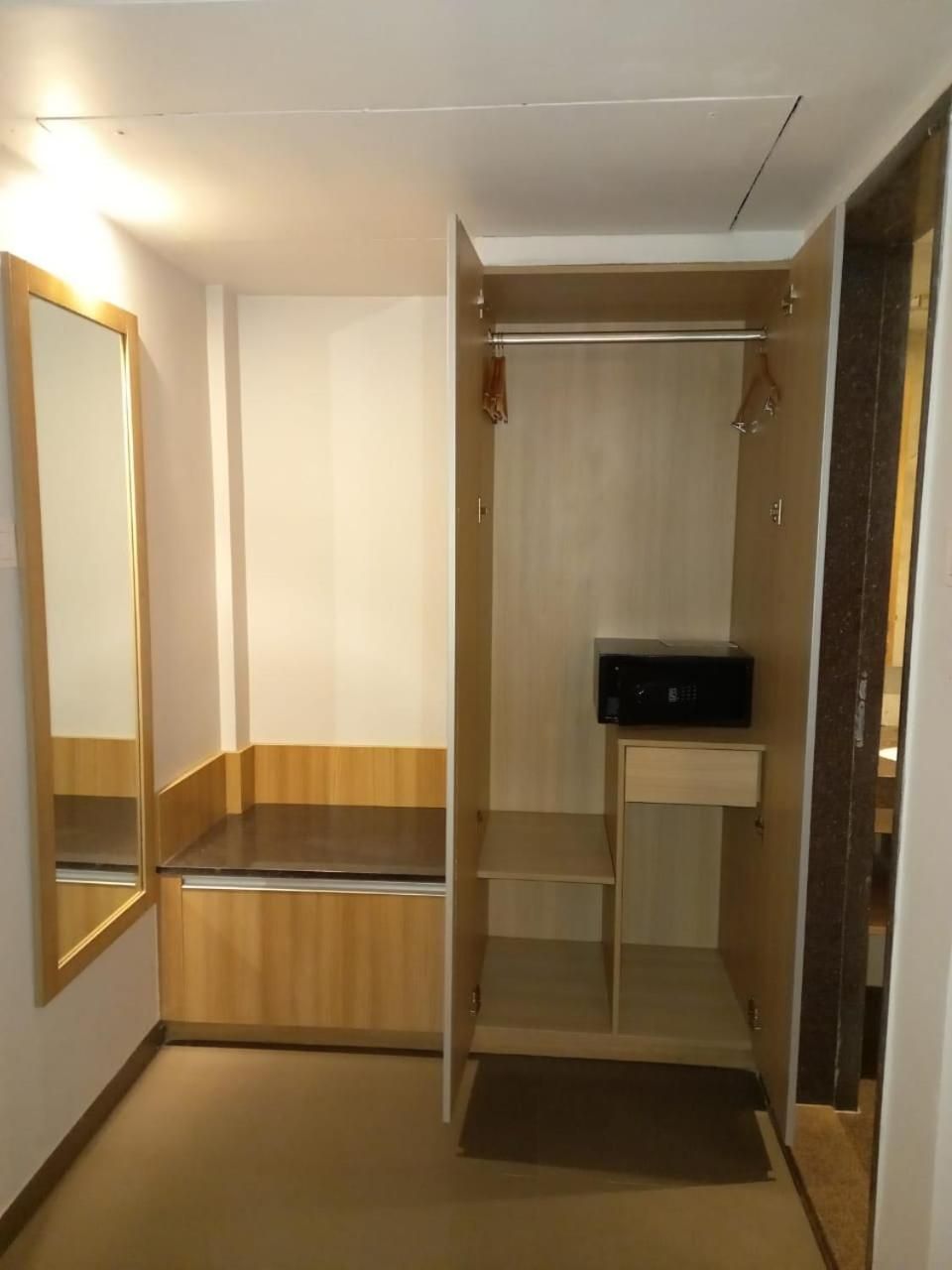 Un closet pequeño con espacio para entrar, un espejo, una barra para colgar ropa y un estante.